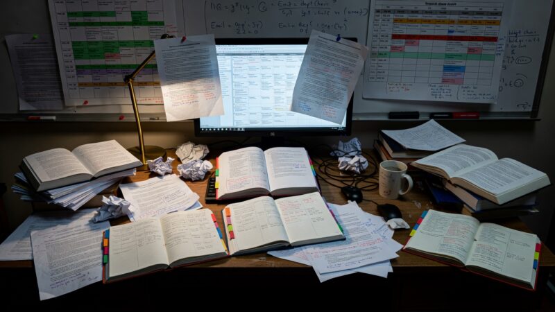 Professor's desk covered with detailed schedules and academic materials
